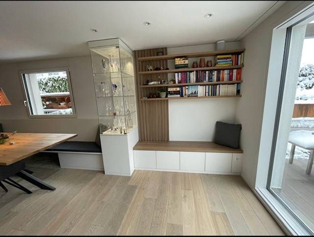 Ein Wohnzimmer mit Tisch, Bank, Bücherregalen und einer Glasschiebetür. Foto von der Schreinerei Hanselmann GmbH