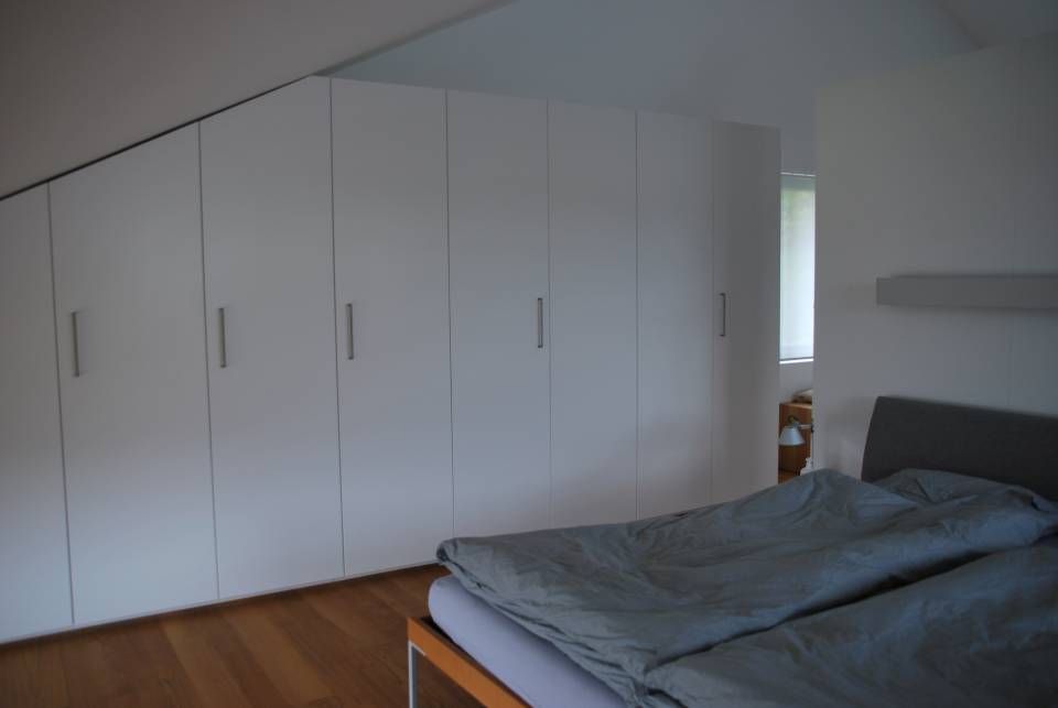 Ein Schlafzimmer mit einem Bett und weissen Schränken. Foto von der Schreinerei Hanselmann GmbH