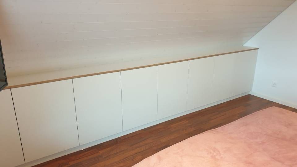 Ein Schlafzimmer mit einem rosa Teppich und weissen Schränken. Foto von der Schreinerei Hanselmann GmbH