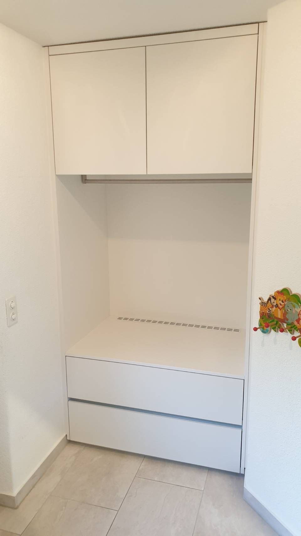 Eine Zimmerecke mit weissen Schränken und Schubladen. Foto von der Schreinerei Hanselmann GmbH