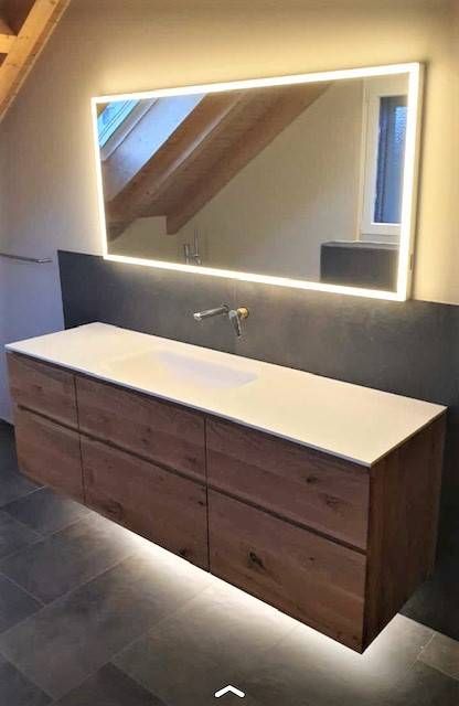 Ein Badezimmer mit Schrank, Waschbecken und einem grossen Spiegel. Foto von der Schreinerei Hanselmann GmbH