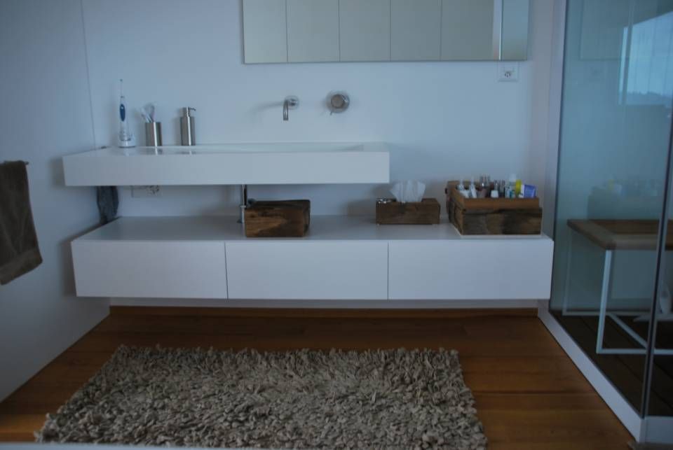 Ein Badezimmer mit Schrank, Waschbecken und einem Teppich auf dem Boden. Foto von der Schreinerei Hanselmann GmbH