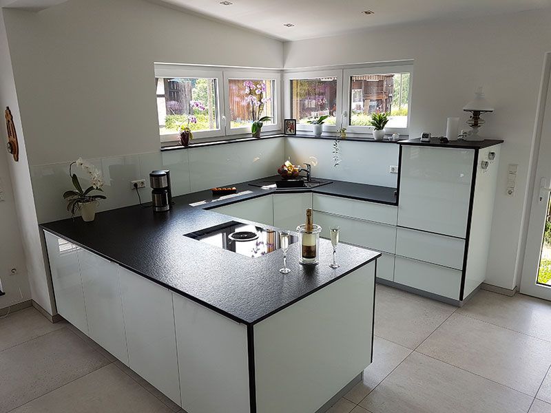 Eine Küche mit schwarzer Arbeitsplatte und weißen Schränken