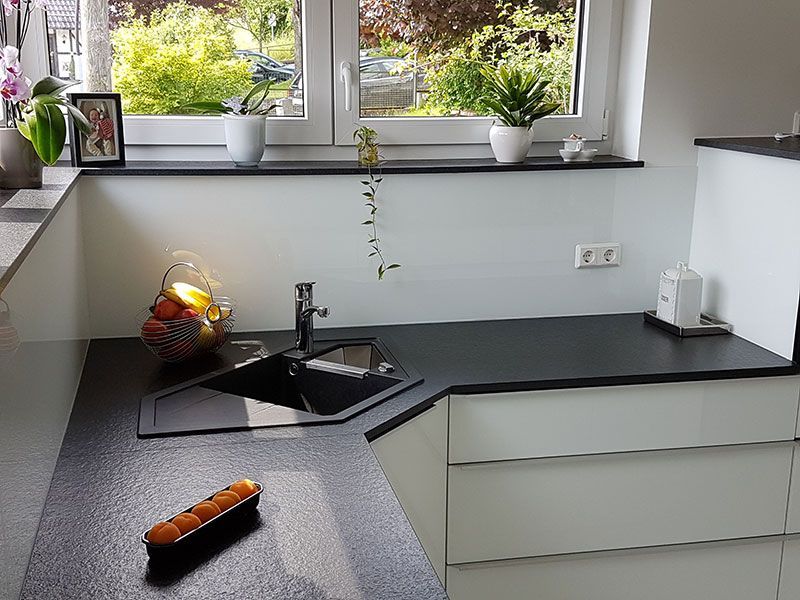 Eine Küche mit Spüle, Schränken und Fenster.