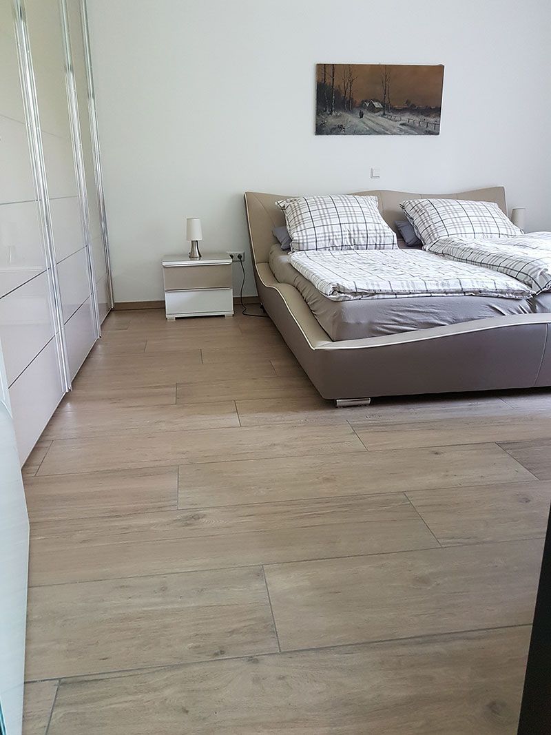 Ein Schlafzimmer mit einem Bett, einem Nachttisch und einem Gemälde an der Wand.