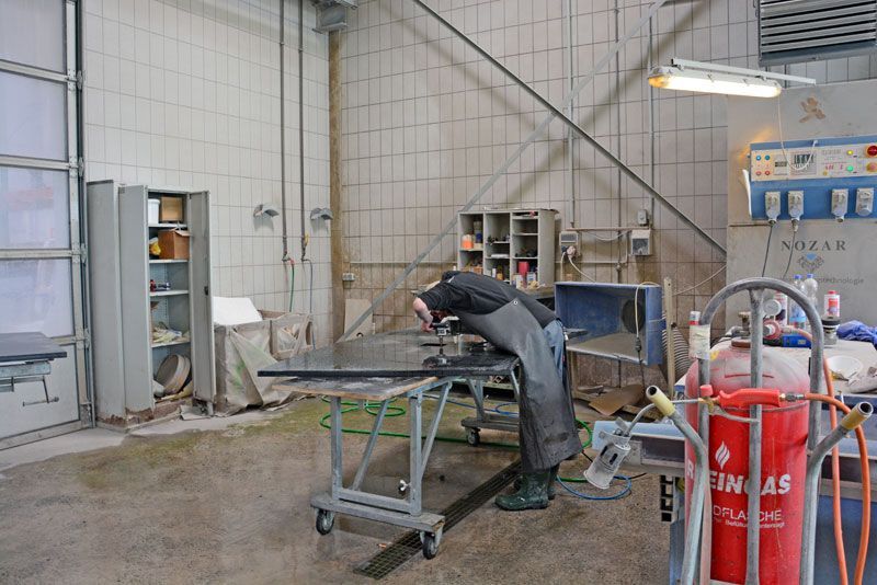 Ein Mann bearbeitet in einer Werkstatt ein Stück Metall.