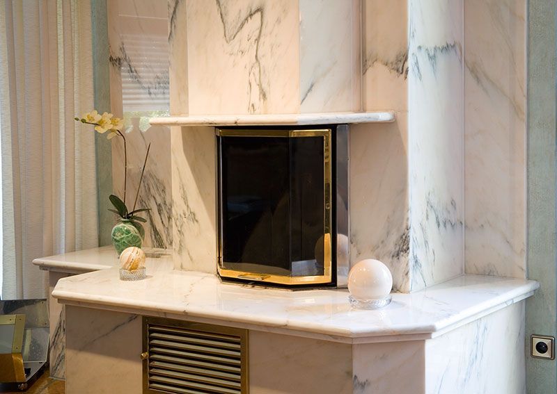 Ein Kamin in einem Wohnzimmer mit Marmorwänden