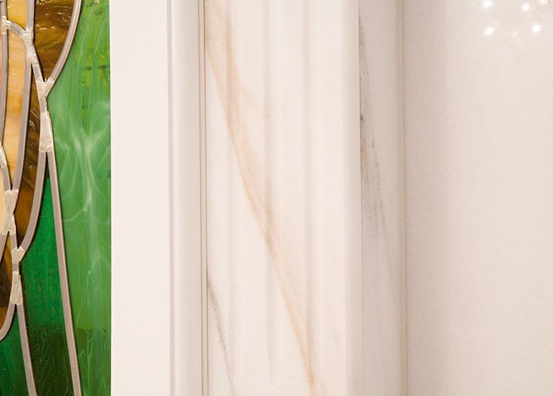 Ein Buntglasfenster in einem Badezimmer neben einer weißen Wand.