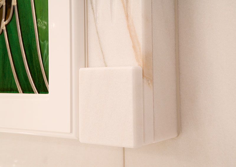 Ein weißer Schrank mit einem grünen Buntglasfenster darin.