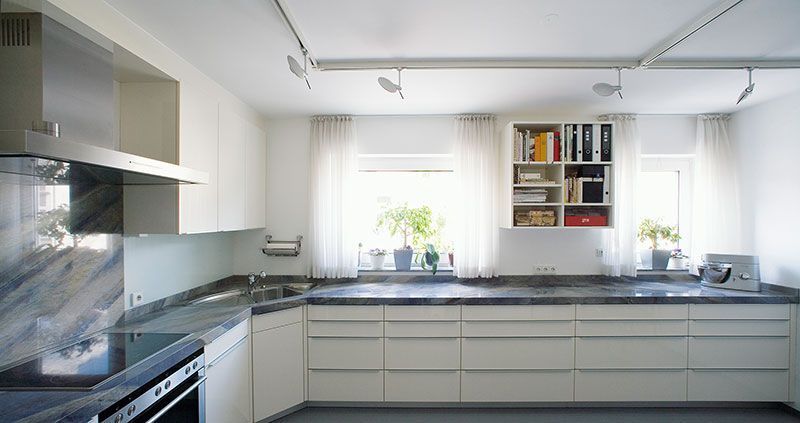 Eine Küche mit weißen Schränken und schwarzen Arbeitsplatten