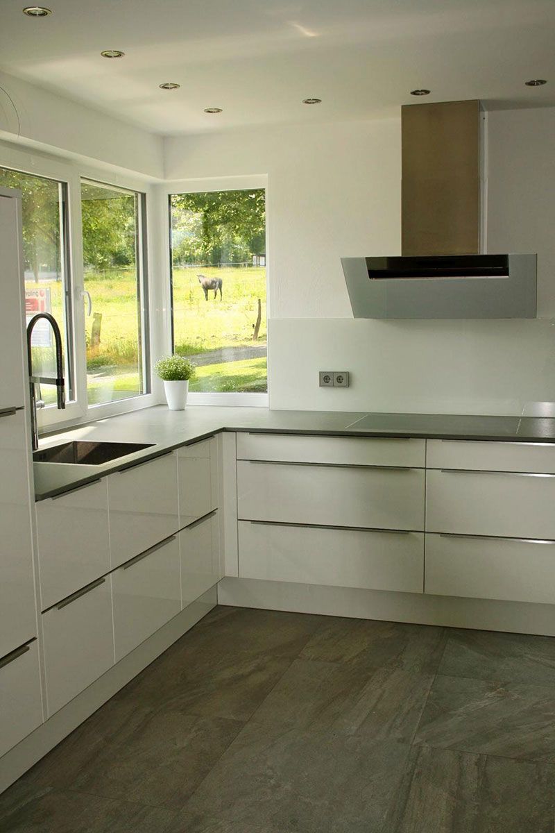 Eine Küche mit weißen Schränken, Geräten aus Edelstahl, einer Spüle und einem Fenster.