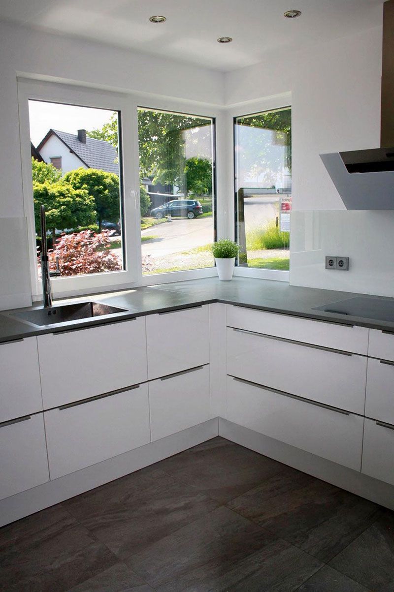 Eine Küche mit weißen Schränken und einem großen Fenster