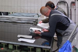 Zwei Männer arbeiten an einem Tisch in einer Fabrik.