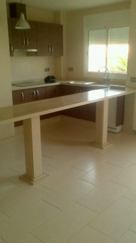 Una cocina vacía con una mesa grande en el medio.