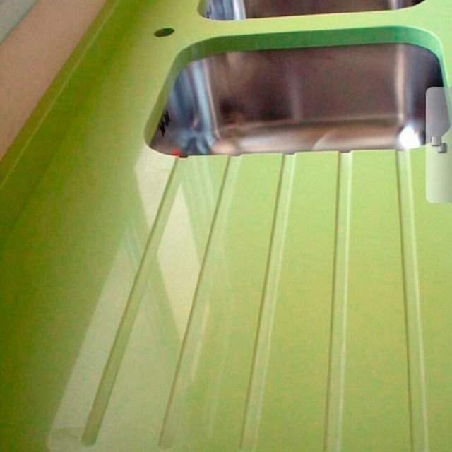 Una encimera verde con un fregadero de acero inoxidable.