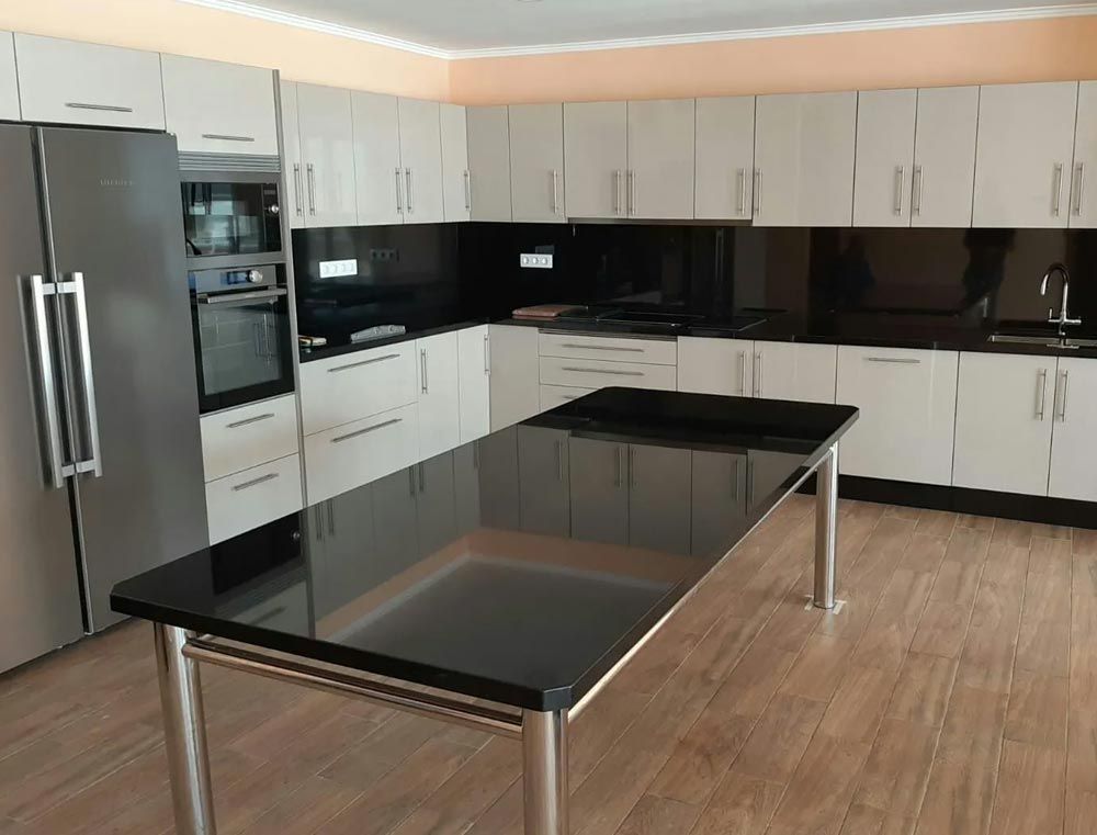 Cocina moderna con armarios blancos, encimeras negras, electrodomésticos de acero inoxidable y una isla central