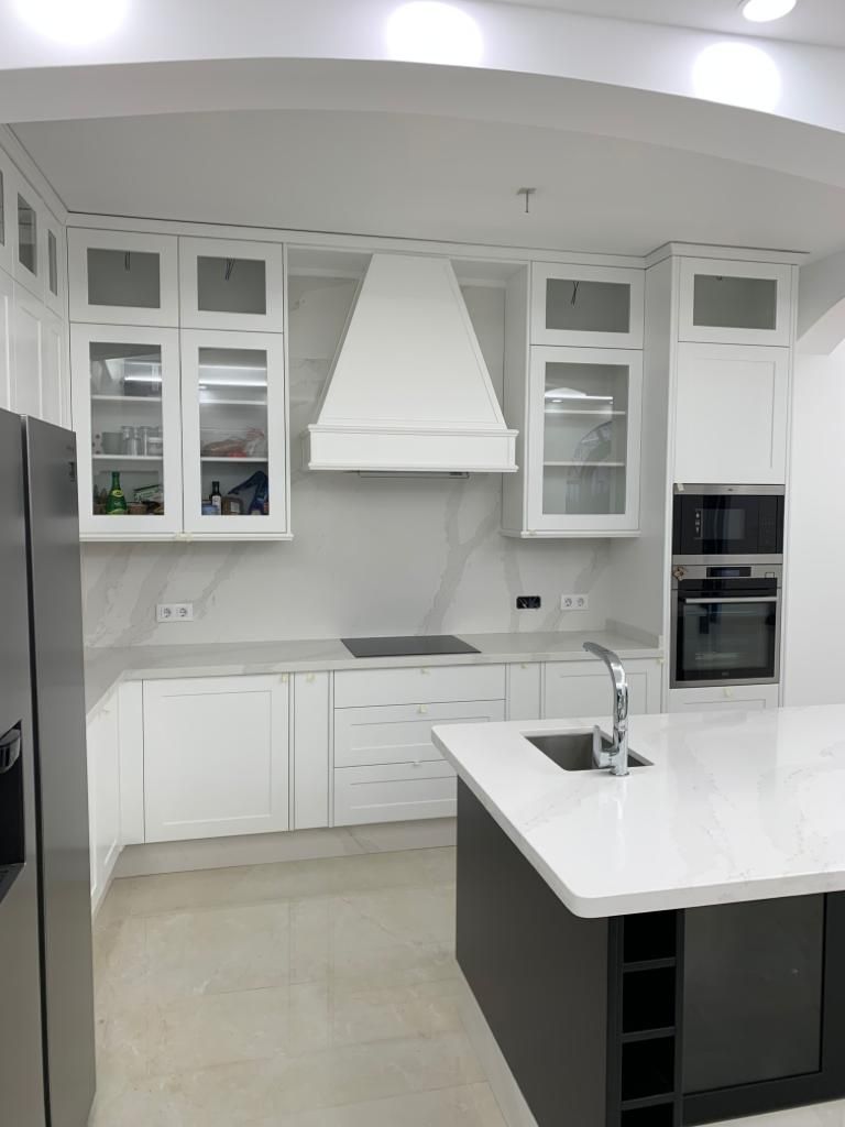 Una cocina con gabinetes blancos y electrodomésticos de acero inoxidable.