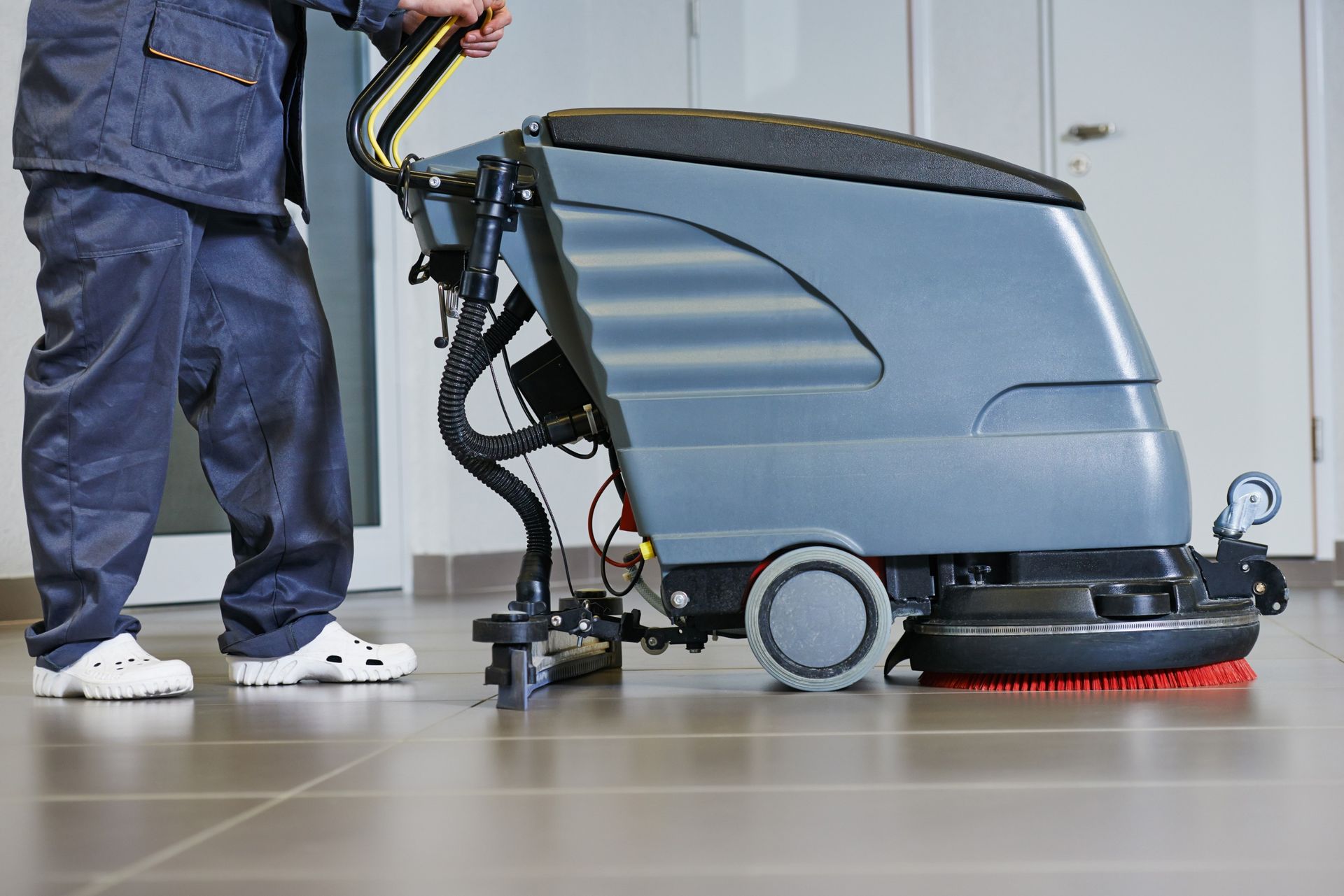 Una persona está usando una máquina para limpiar un piso de baldosas.