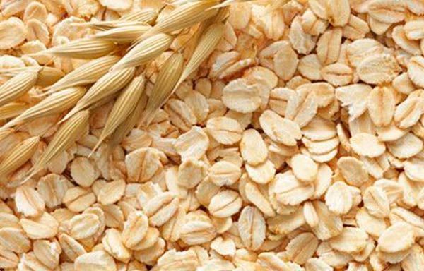 Un montón de avena y espigas de avena sobre una mesa.