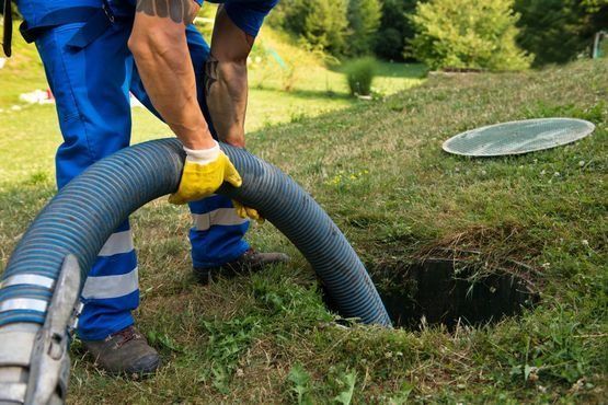 Un hombre está bombeando agua a un tanque séptico con una manguera.