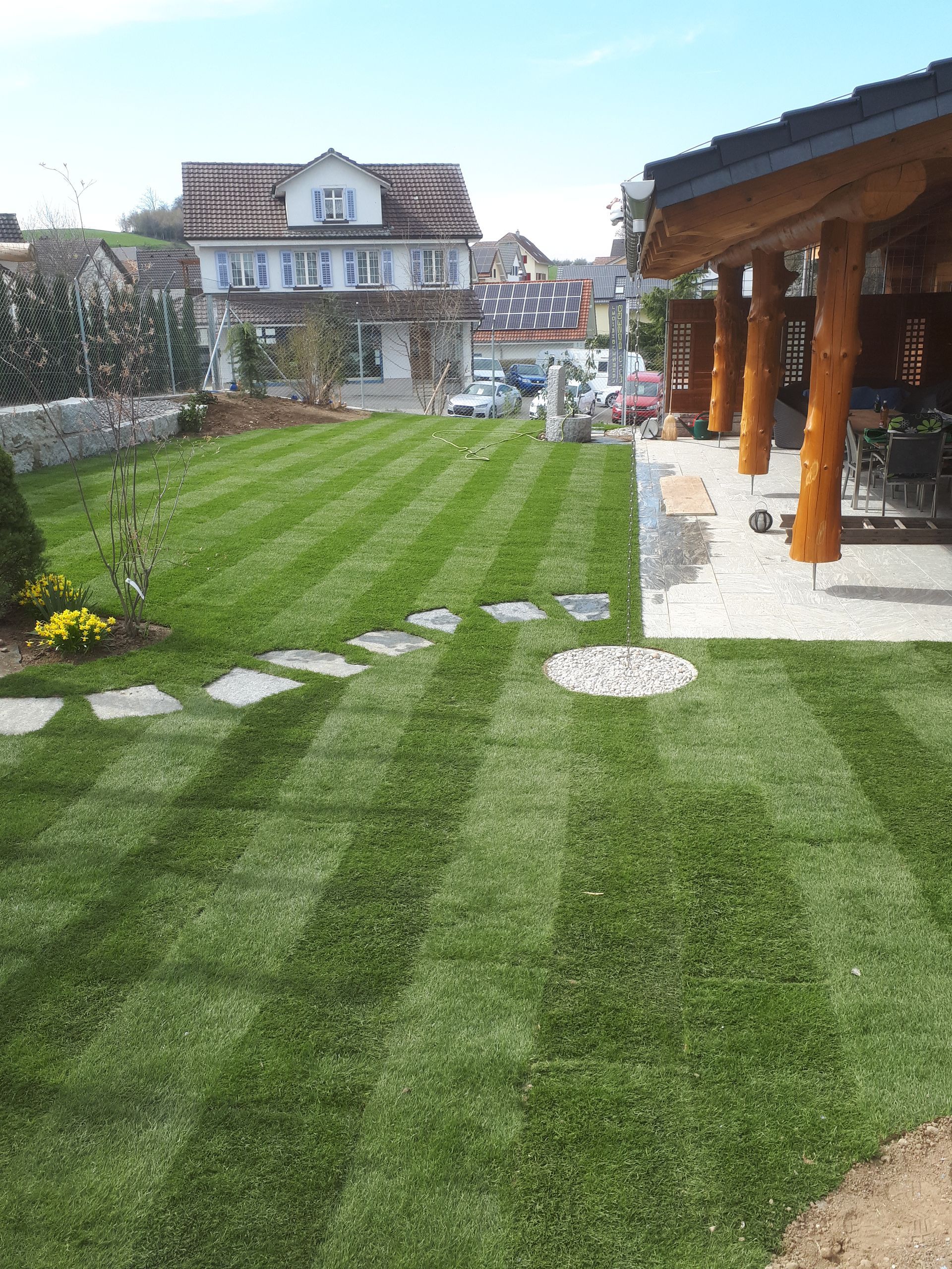A lush green lawn with a house in the background