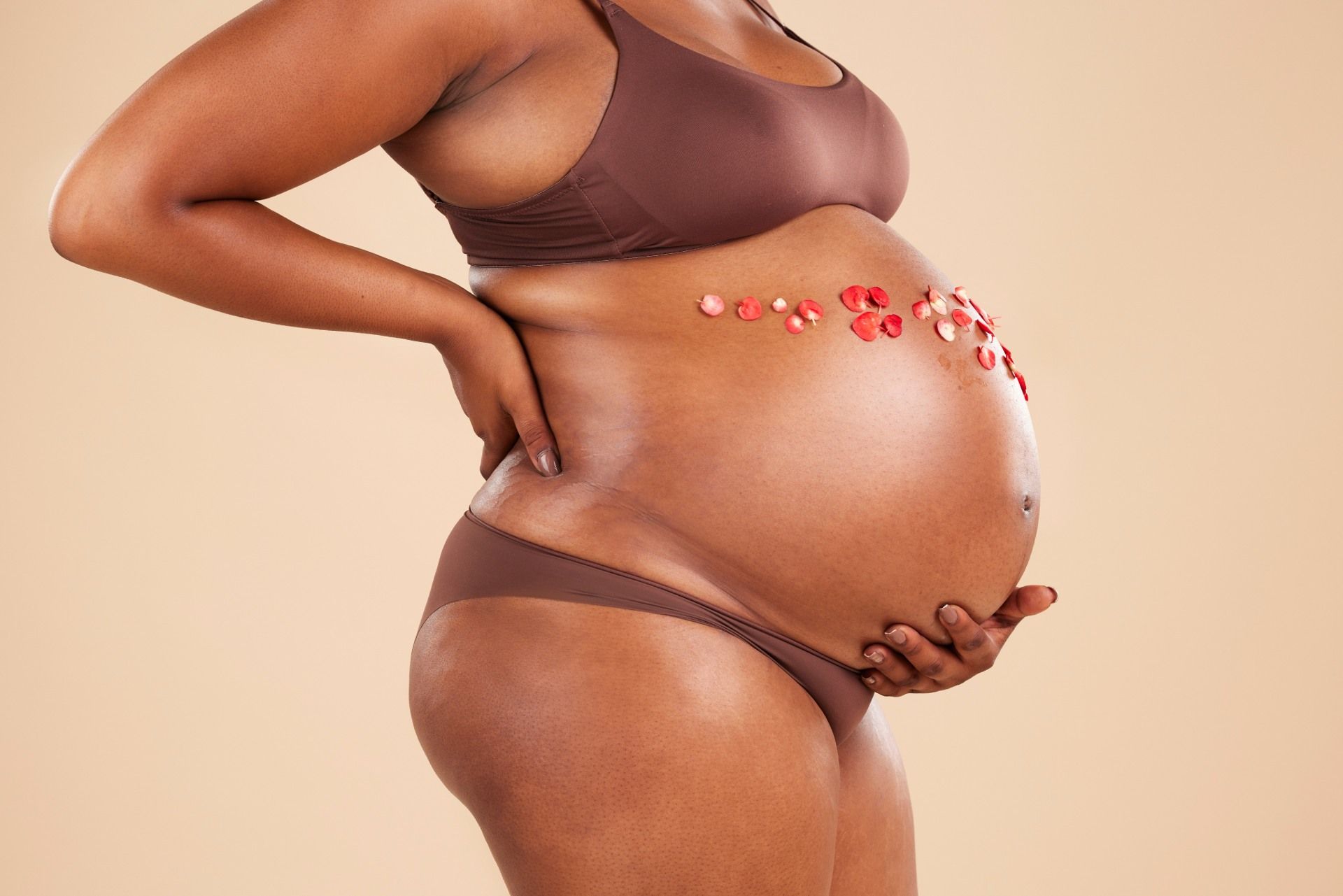 Une femme enceinte en sous-vêtements tient son ventre.