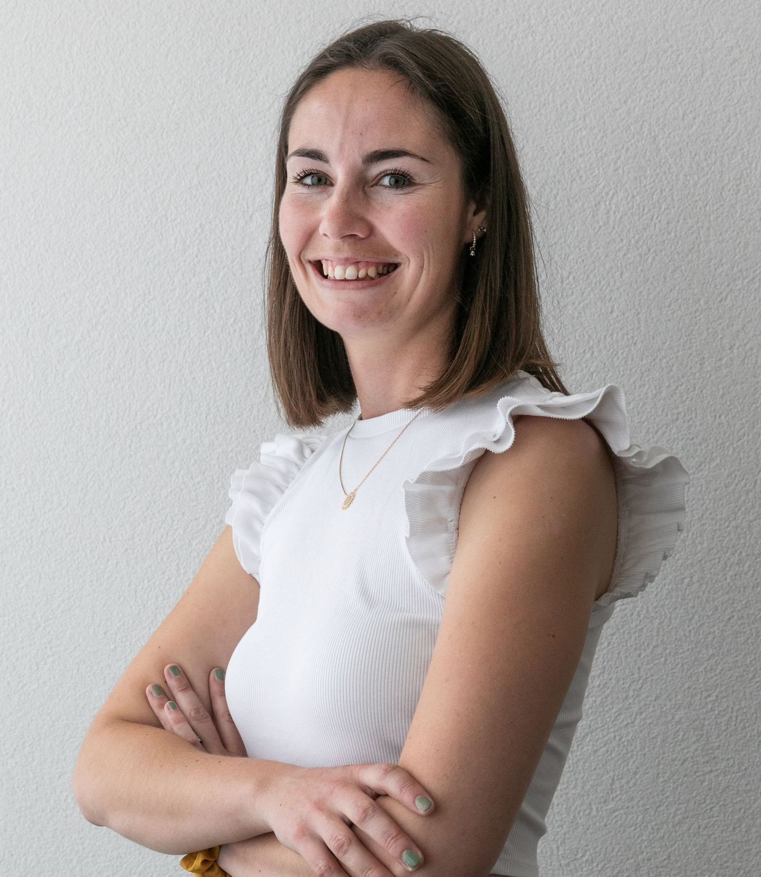 Une femme portant des lunettes et une chemise blanche sourit à la caméra.