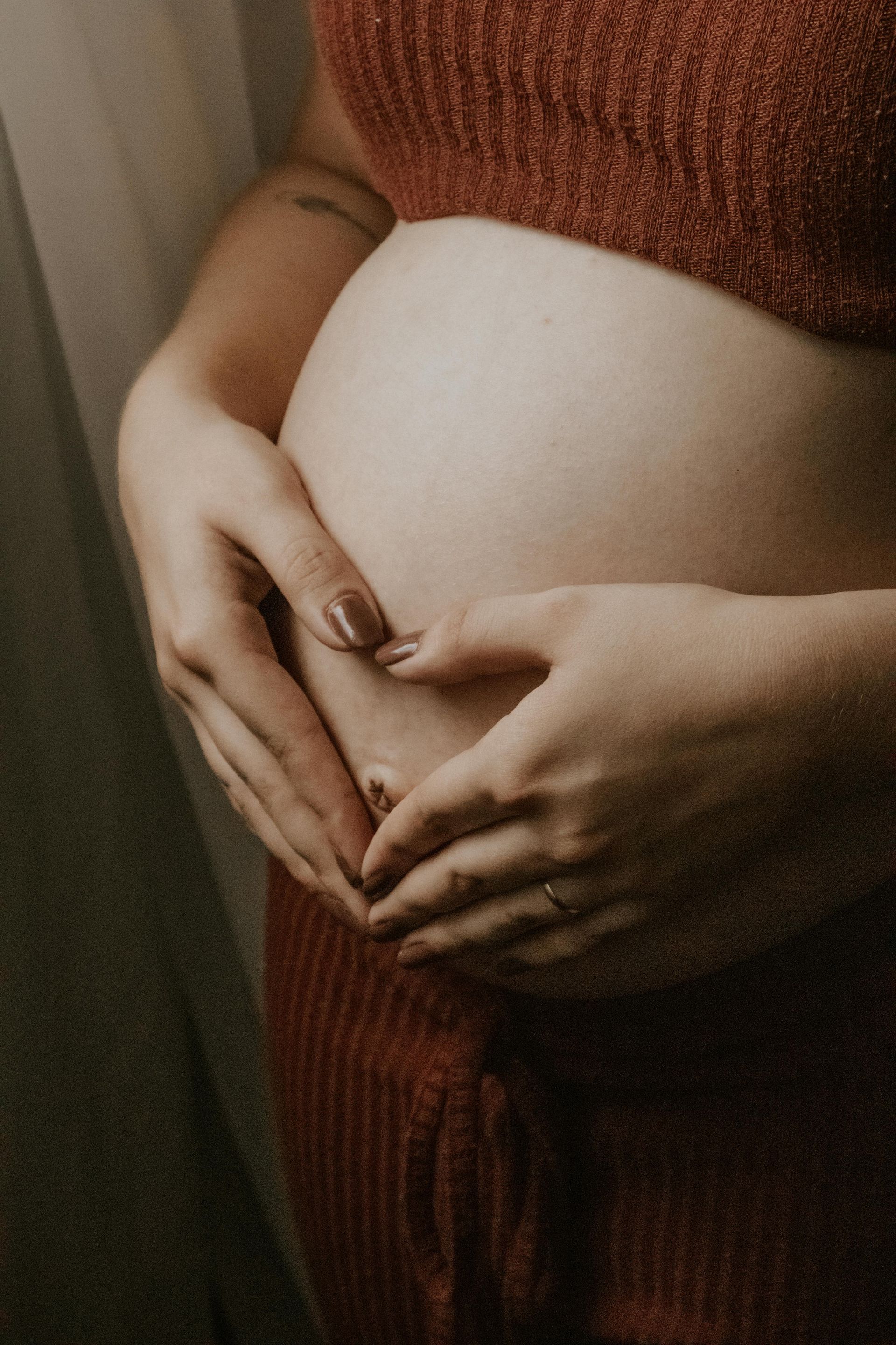 Une femme enceinte en sous-vêtements tient son ventre.