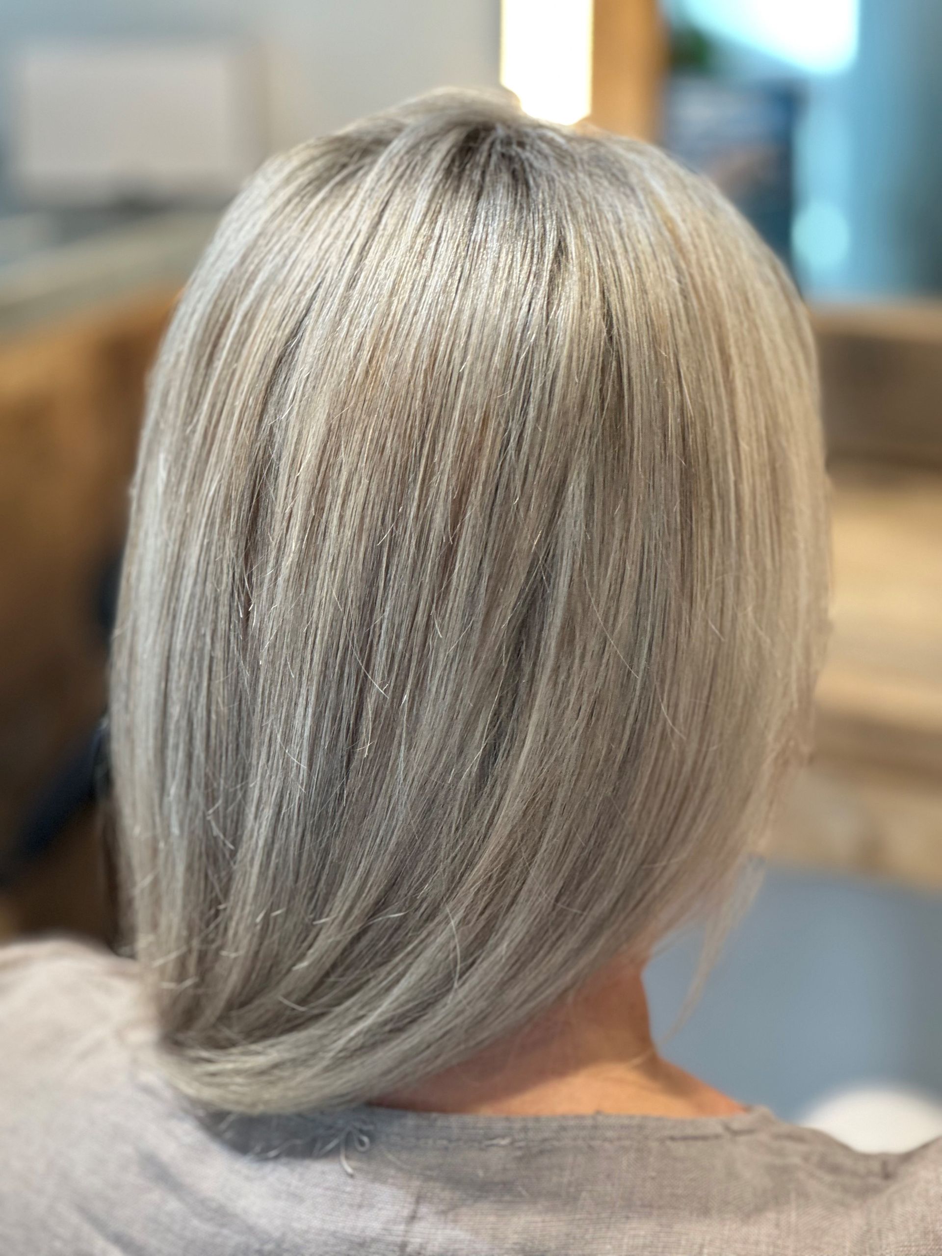 Der Hinterkopf einer Frau mit langen grauen Haaren.