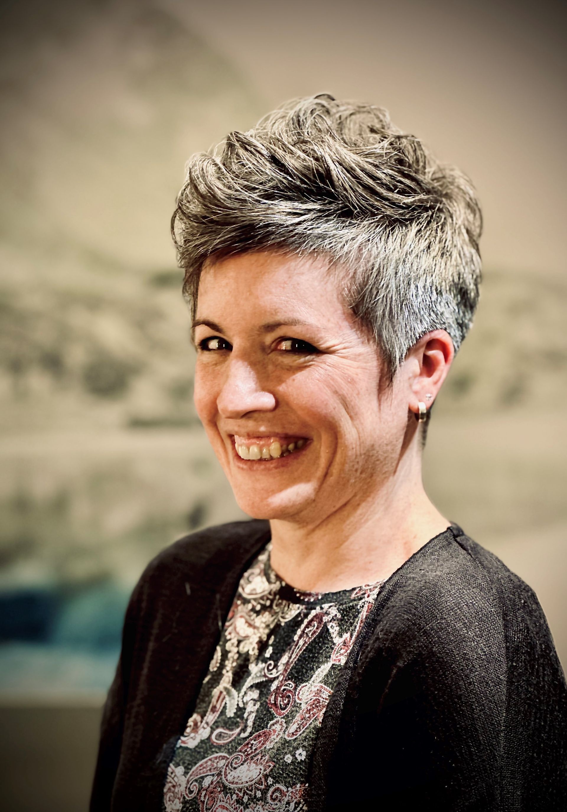 Eine Frau mit kurzen Haaren lächelt in die Kamera.