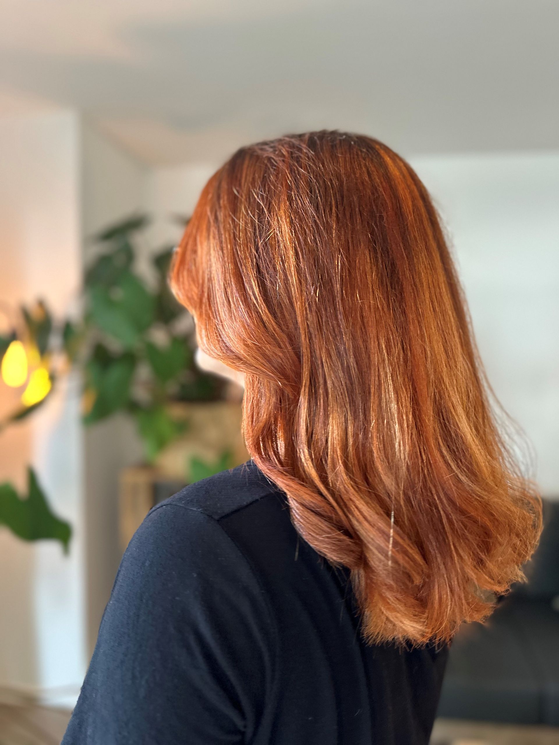 Eine Frau mit roten Haaren und einem schwarzen Hemd steht in einem Wohnzimmer.