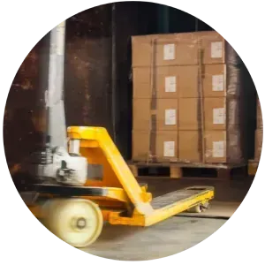 Una carretilla manual amarilla está moviendo un palé de cajas en un almacén.