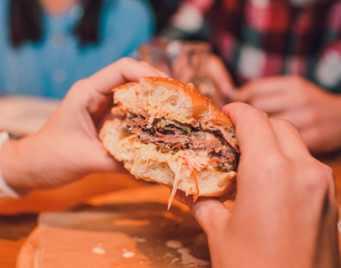 Una persona sostiene una hamburguesa en sus manos.