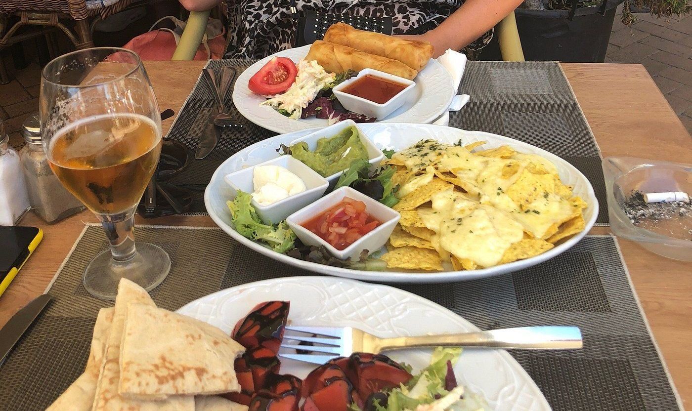 A table topped with plates of food and a glass of beer.