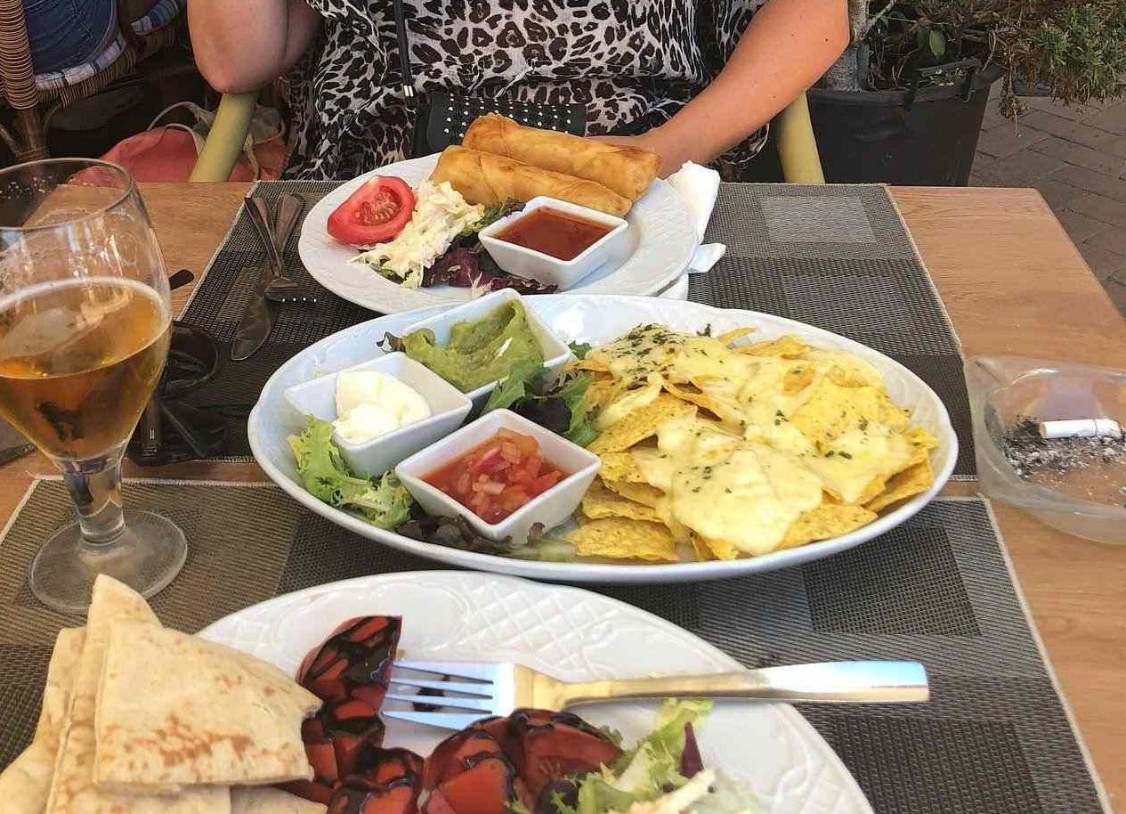 Una mesa cubierta con platos de comida y un vaso de cerveza.