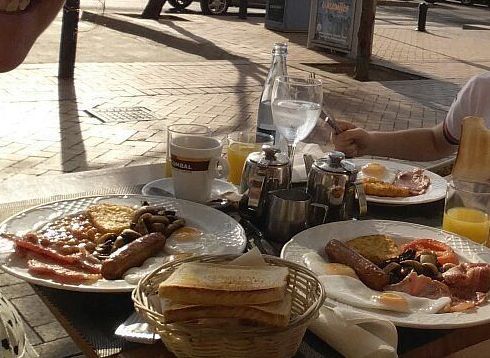 Una persona está sentada en una mesa con platos de comida sobre ella.