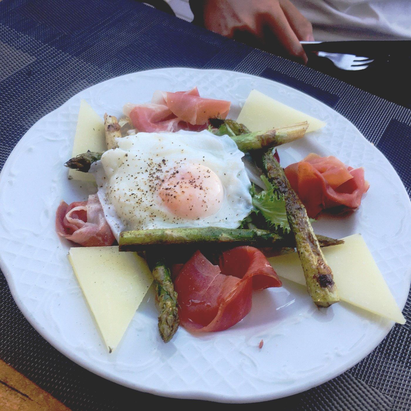 A white plate topped with eggs asparagus cheese and ham