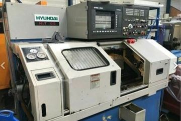 Torno CNC Hyundai HLT 8S, color blanco y gris, controles en la parte superior, en un taller.