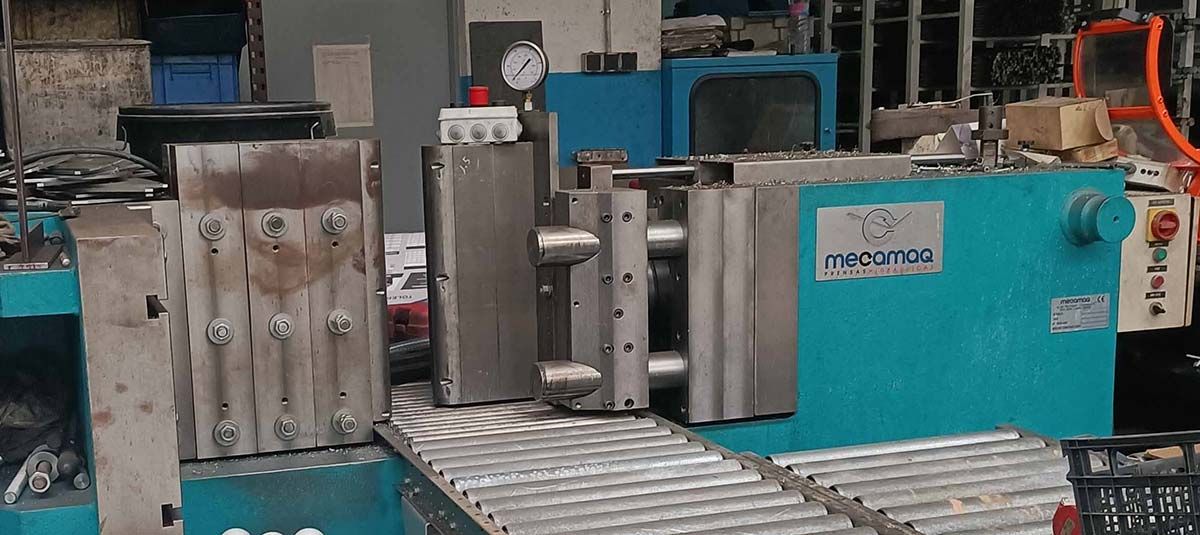 Maquina industrial con componentes plateados y azules y manómetro.