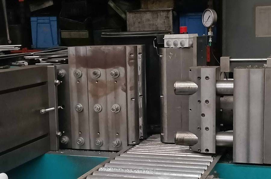 Piezas de molde de metal en una cinta transportadora en un entorno industrial.