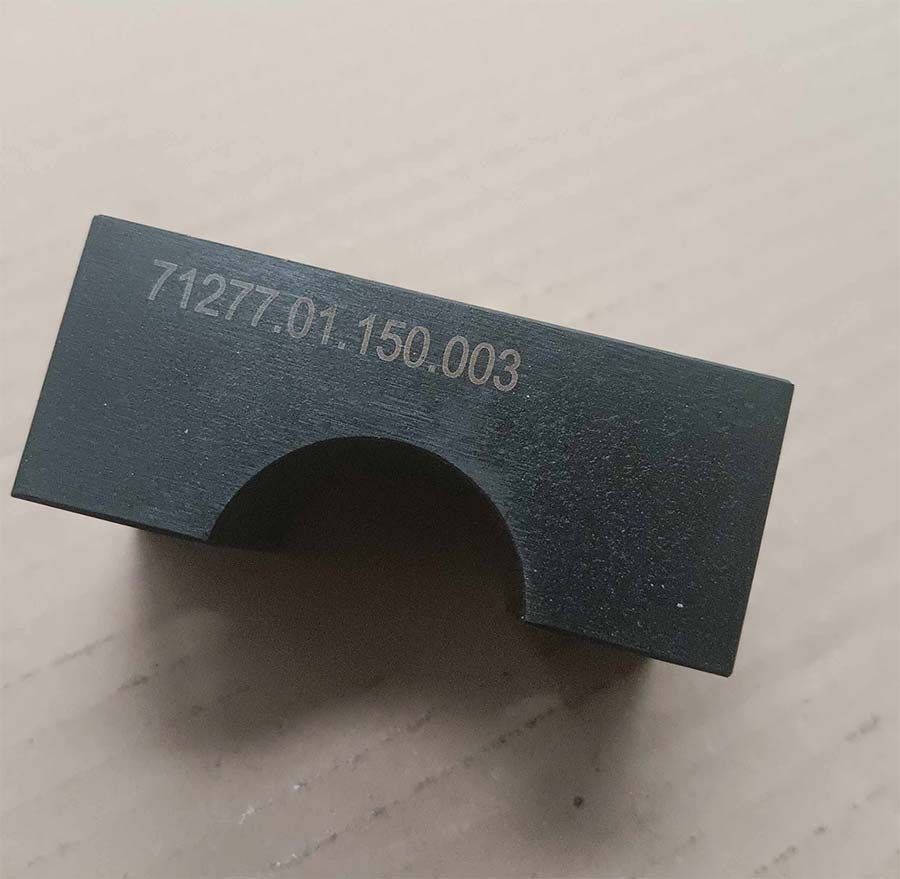 Pieza metálica rectangular de color negro con corte semicircular, grabado con el número “71277.01.150.003”.