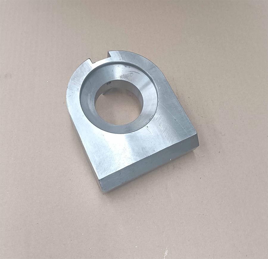 Soporte de metal plateado con un orificio circular, una base plana y una ranura en la parte superior.