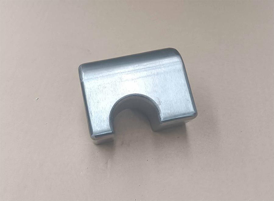 Soporte de metal plateado con recorte curvo sobre superficie beige.