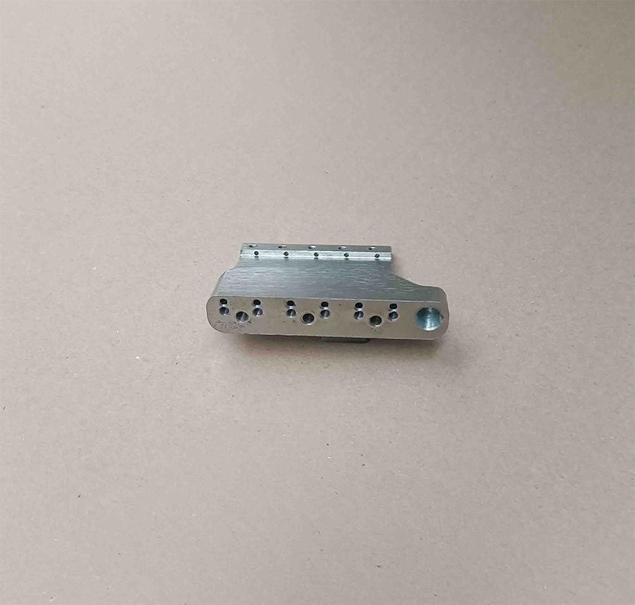 Puente de guitarra metálico con seis agujeros para cuerdas y clavijas de afinación.