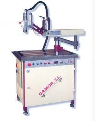 Máquina industrial con mueble color crema, brazo metálico y logo Gamor SL.