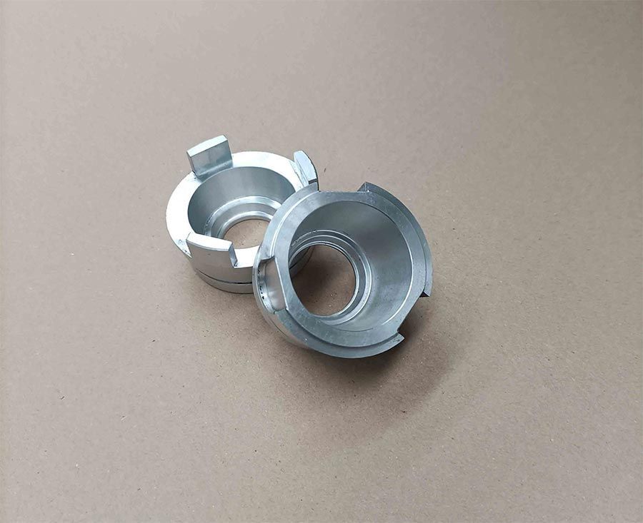 Dos adaptadores de faros para automóviles de metal plateado sobre una superficie color bronce.