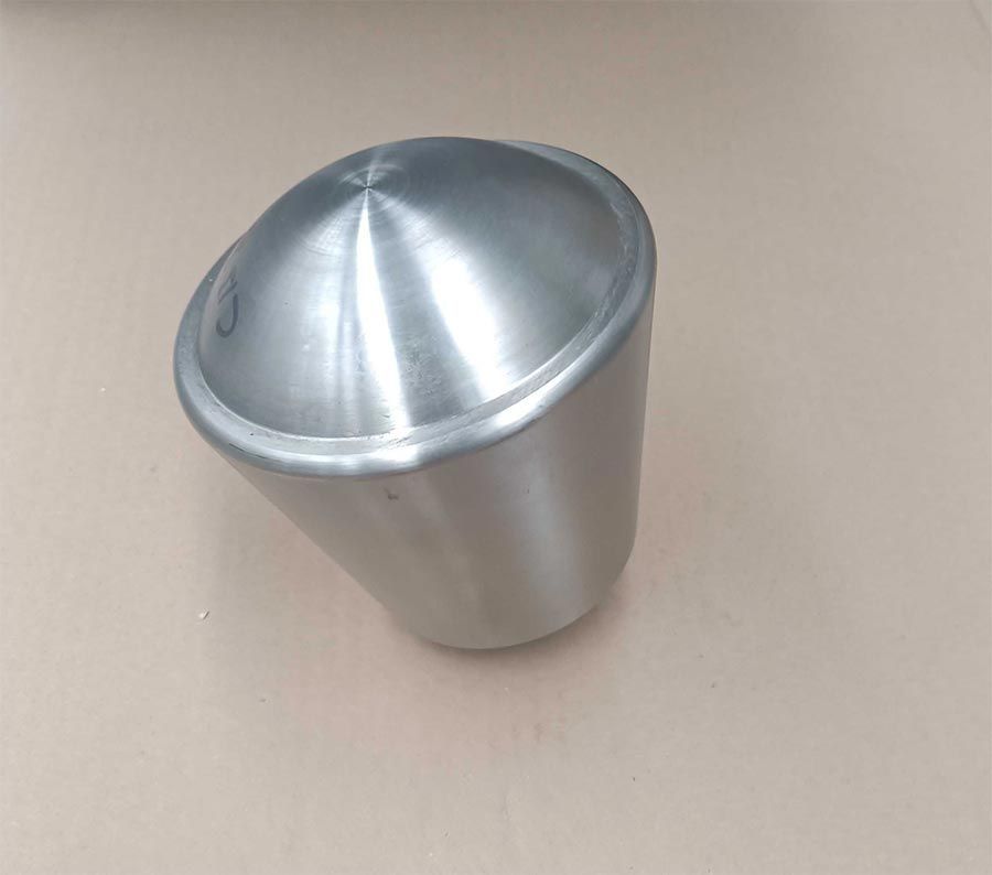 Un recipiente cilíndrico, metálico y inclinado, con la parte superior en forma de cúpula, colocado sobre una superficie clara.