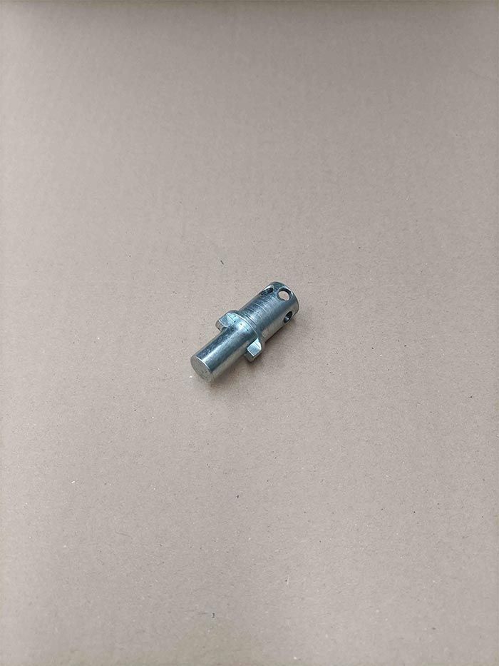 Conector de metal plateado sobre superficie marrón claro.