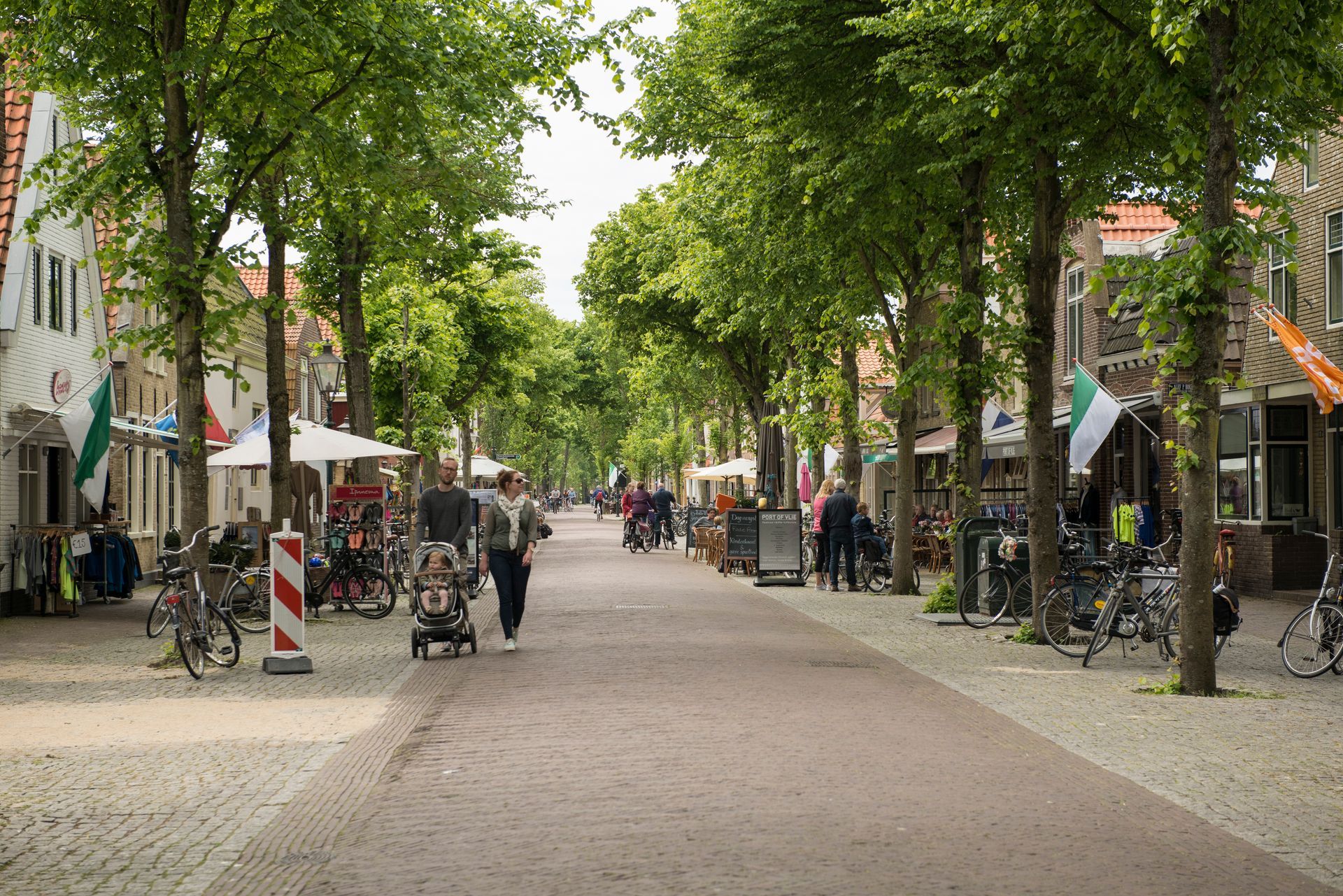 Iemand loopt over een geplaveide straat met bomen.