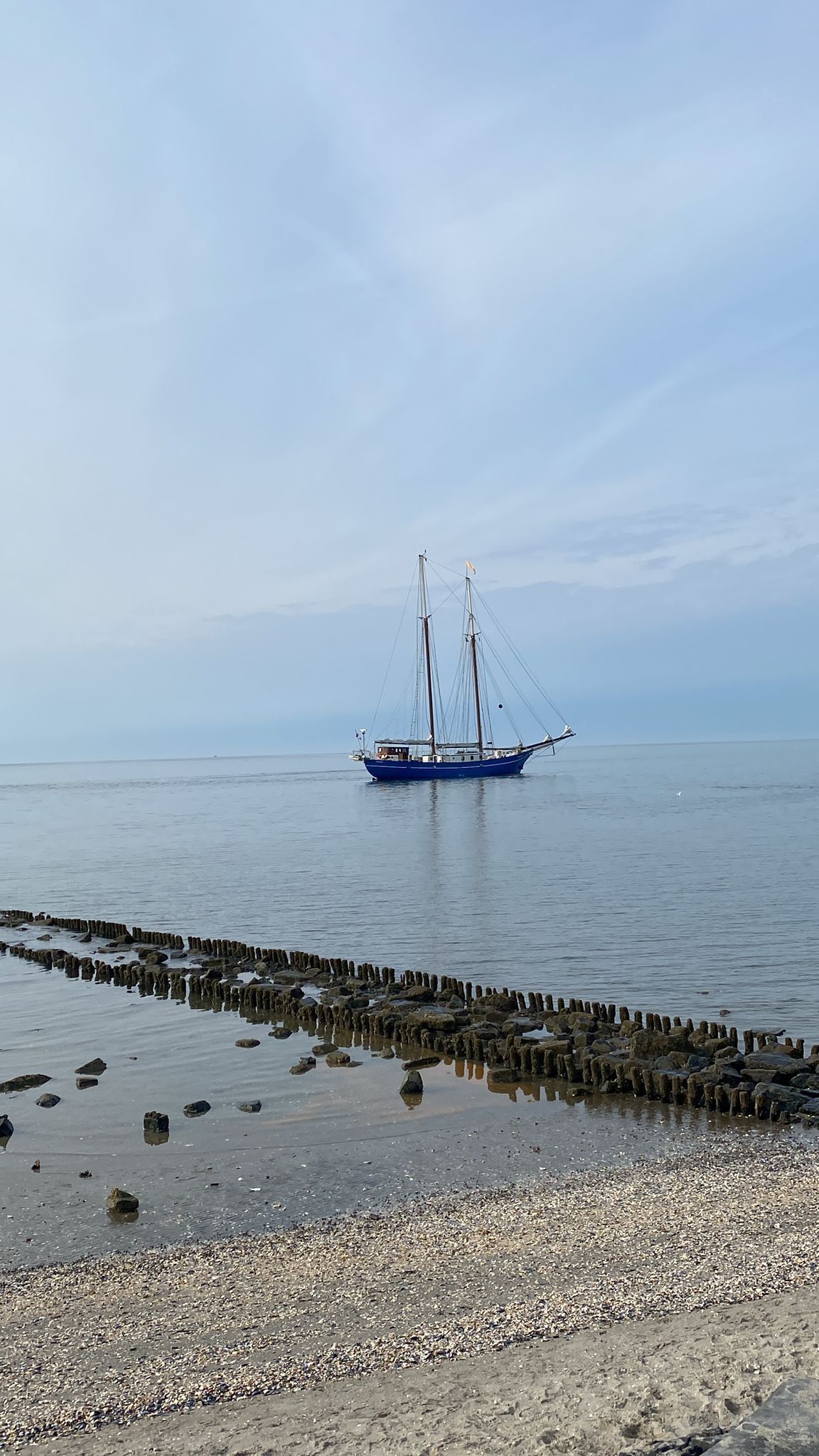 Een boot drijft op een watermassa naast een strand.